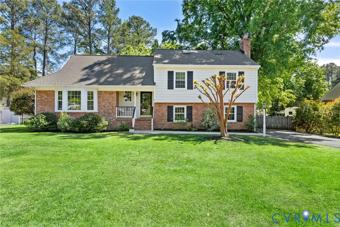 Two-story house with brick and white siding, black shutters, and a green lawn.