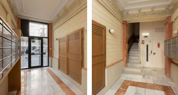 Apartment building lobby with mailboxes, marble floors, and an exit door to the street. Stairs and an elevator are visible.