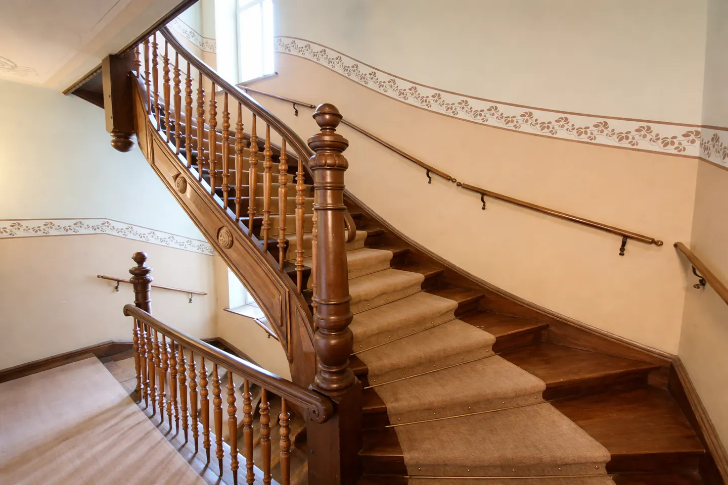 A carpeted wooden staircase with a decorative floral border on the wall.