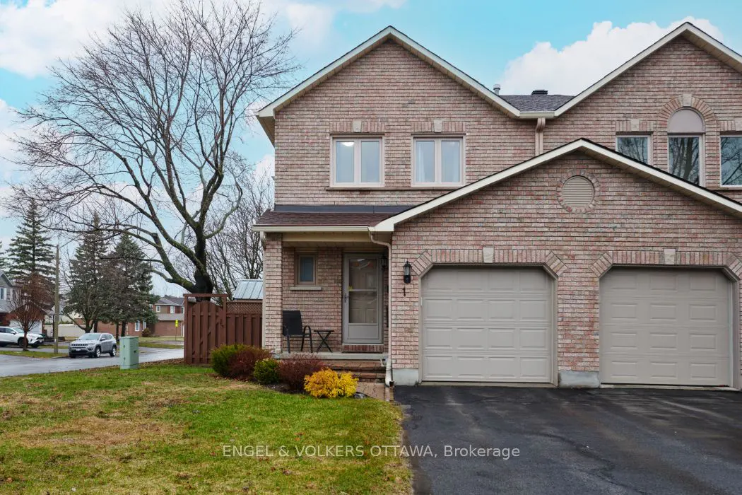 Two-story brick townhouse with two-car garage, small porch, and lawn. Bare tree in the front yard.