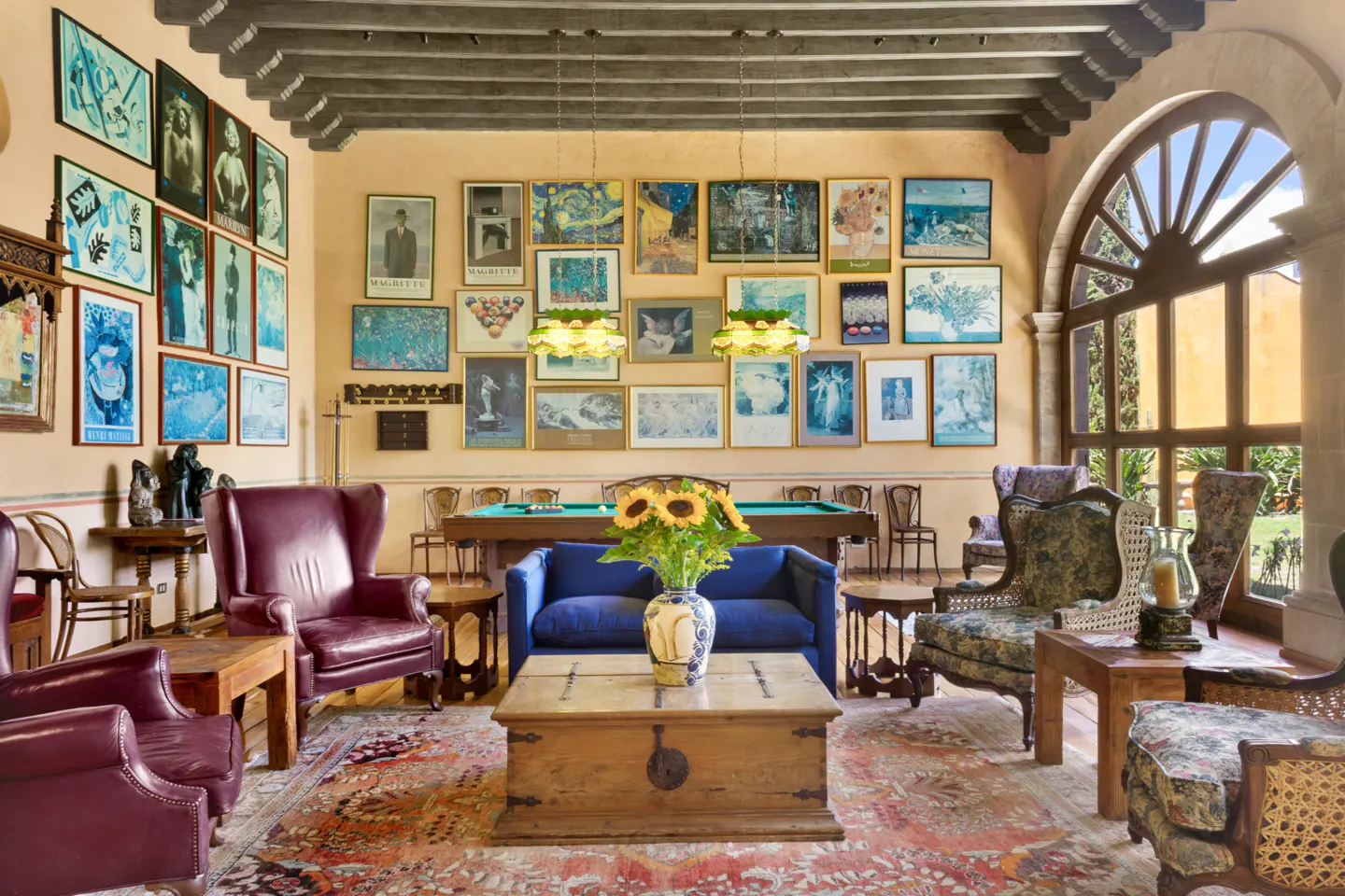 A living room with a pool table, blue sofa, and many framed pictures on the walls.