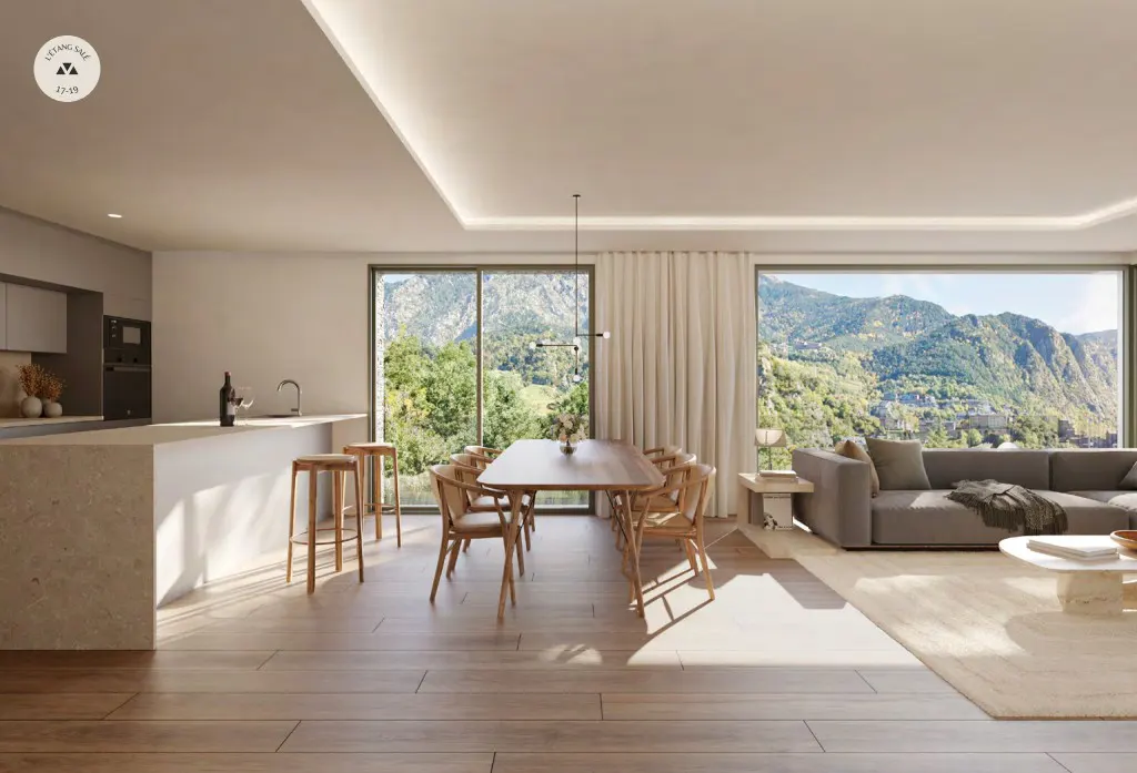 Bright, modern open-plan living space with kitchen island, dining table, and gray sofa. Large windows offer mountain views.