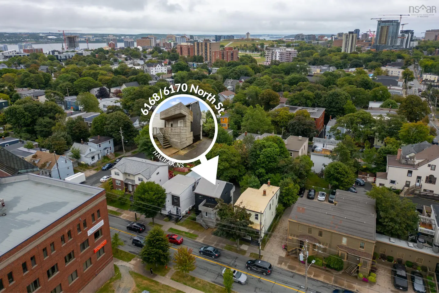Aerial view of 6168/6170 North St, Halifax, NS, surrounded by trees and city buildings. A white circle highlights the property.