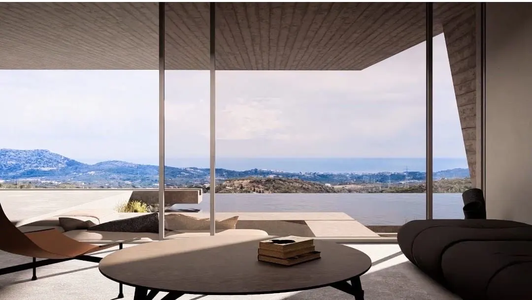 A modern living room with a view. A round table with books sits in front of a large window overlooking the ocean and mountains.