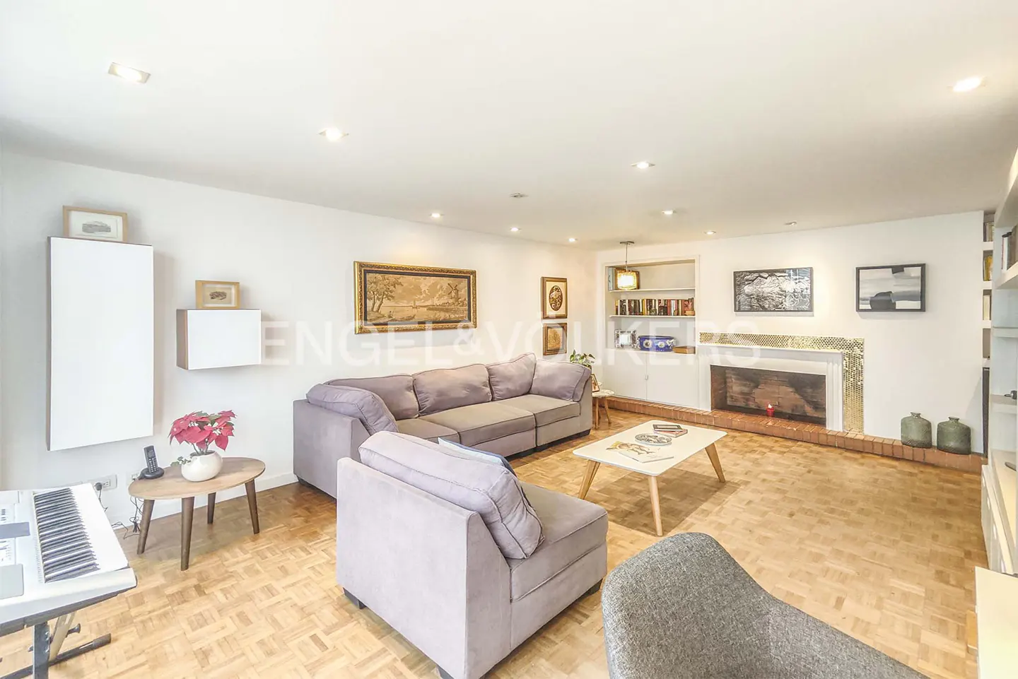 Bright living room with hardwood floors, a gray sectional sofa, a white coffee table, and a fireplace.