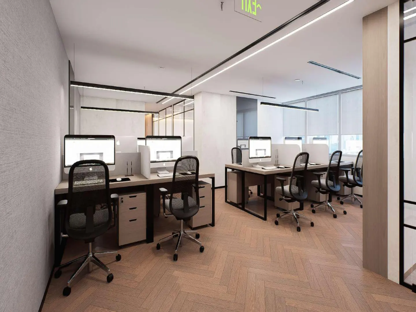 Bright office space with desks, computers, and black mesh chairs on a herringbone wood floor. An exit sign is visible.