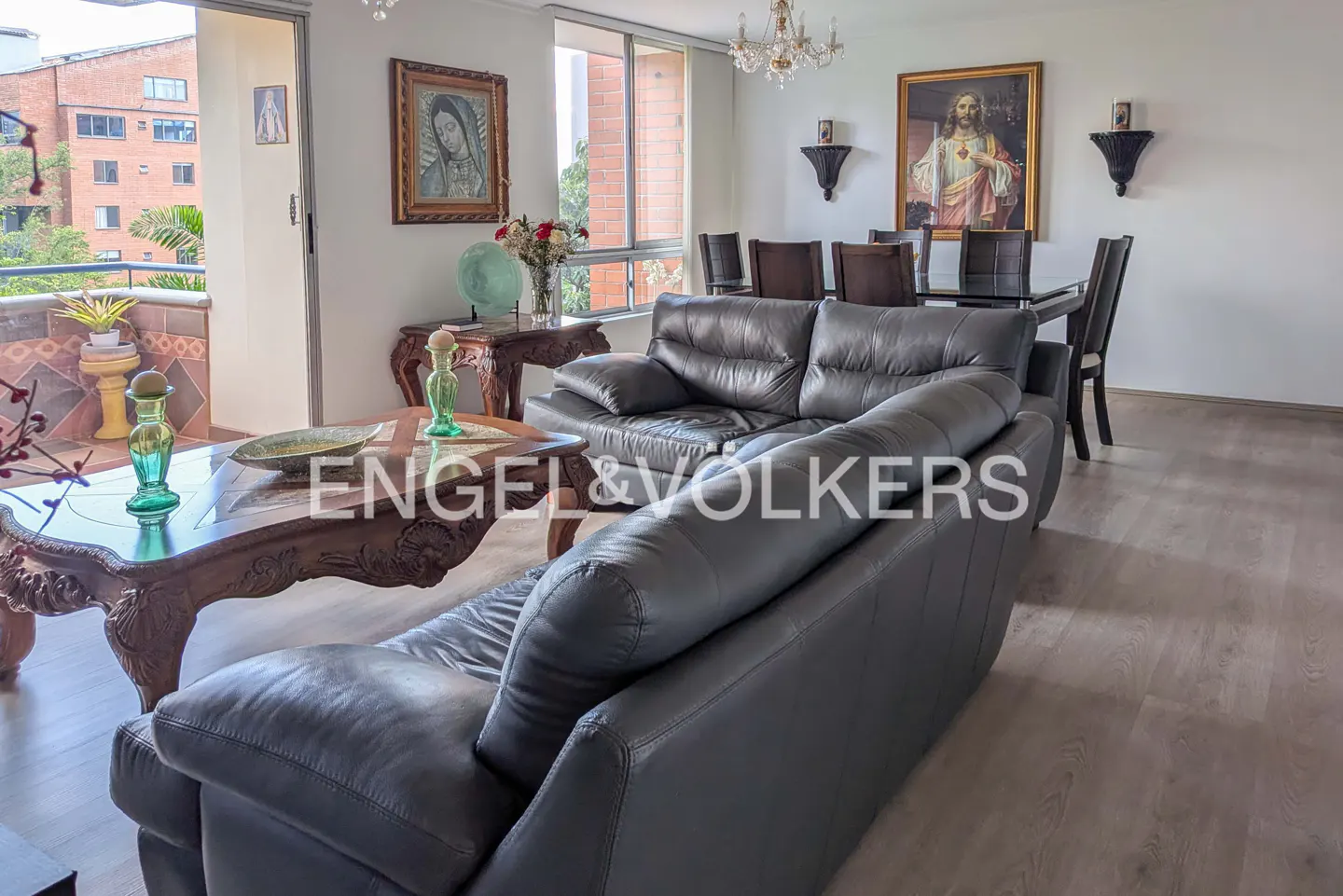 A living room with gray leather sofas, a carved wood coffee table, and a dining table with chairs.