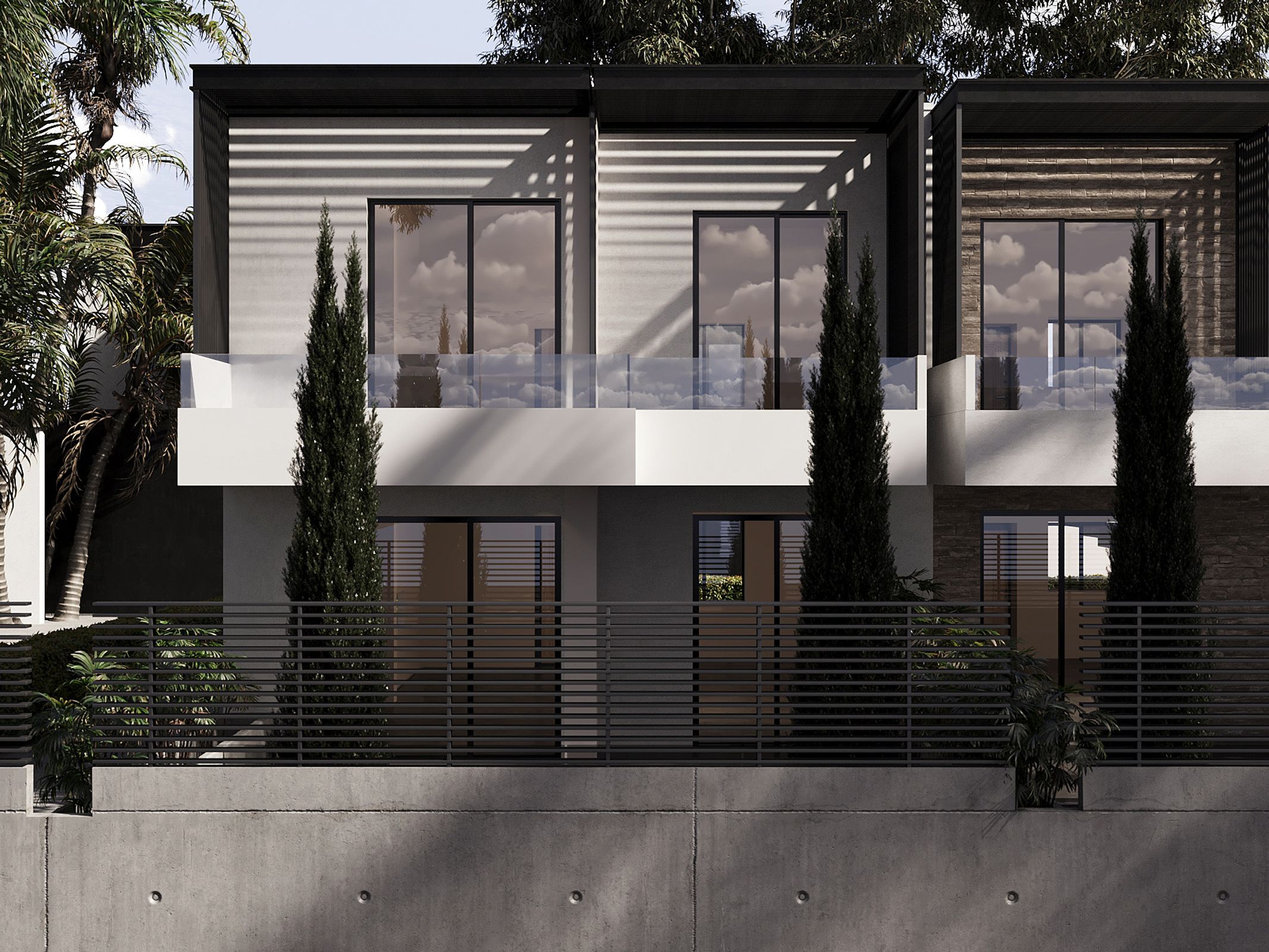 Modern townhouses with black trim, white walls, and glass balconies. Tall, thin trees line the front, behind a black metal fence and concrete wall.