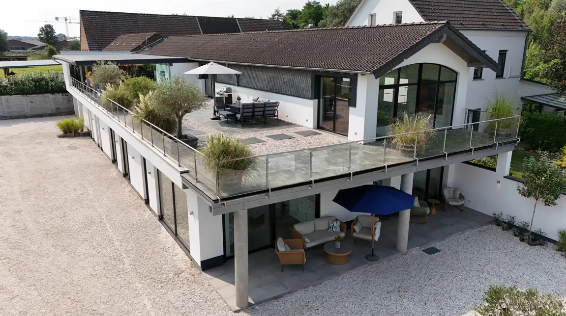 Aerial view of a modern white house with a rooftop terrace and outdoor seating areas.