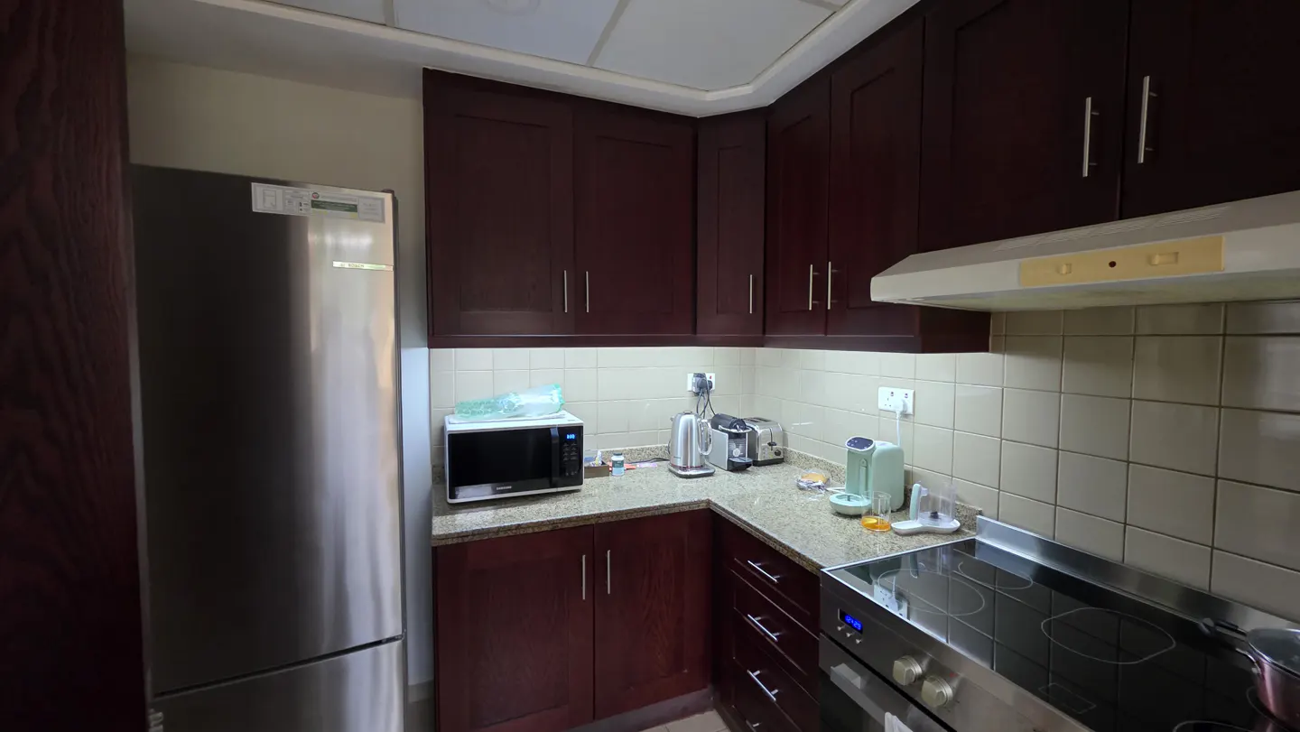 Kitchen with dark wood cabinets, granite countertops, stainless steel refrigerator, and a black electric stovetop.