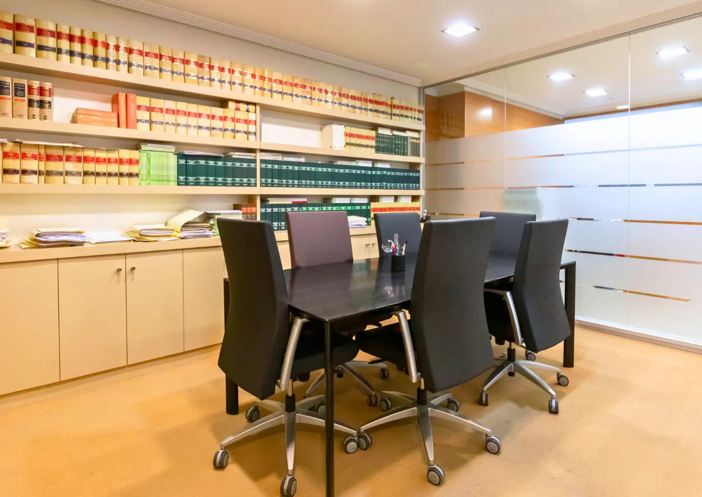 Conference room with a dark table, black chairs, and shelves of law books.