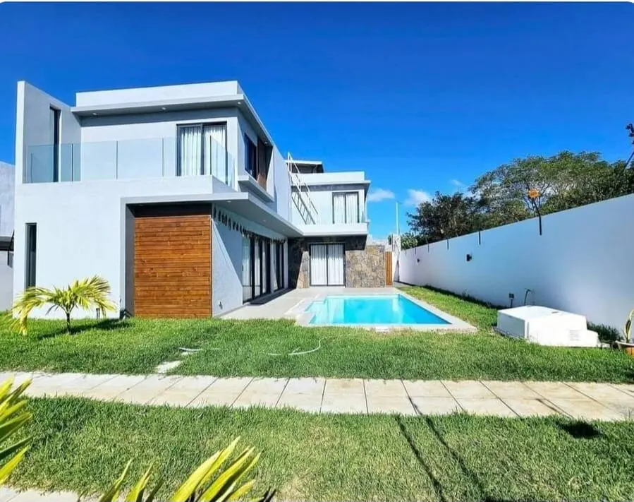 Modern two-story house with a pool. The house is white with wood and stone accents, set against a blue sky.