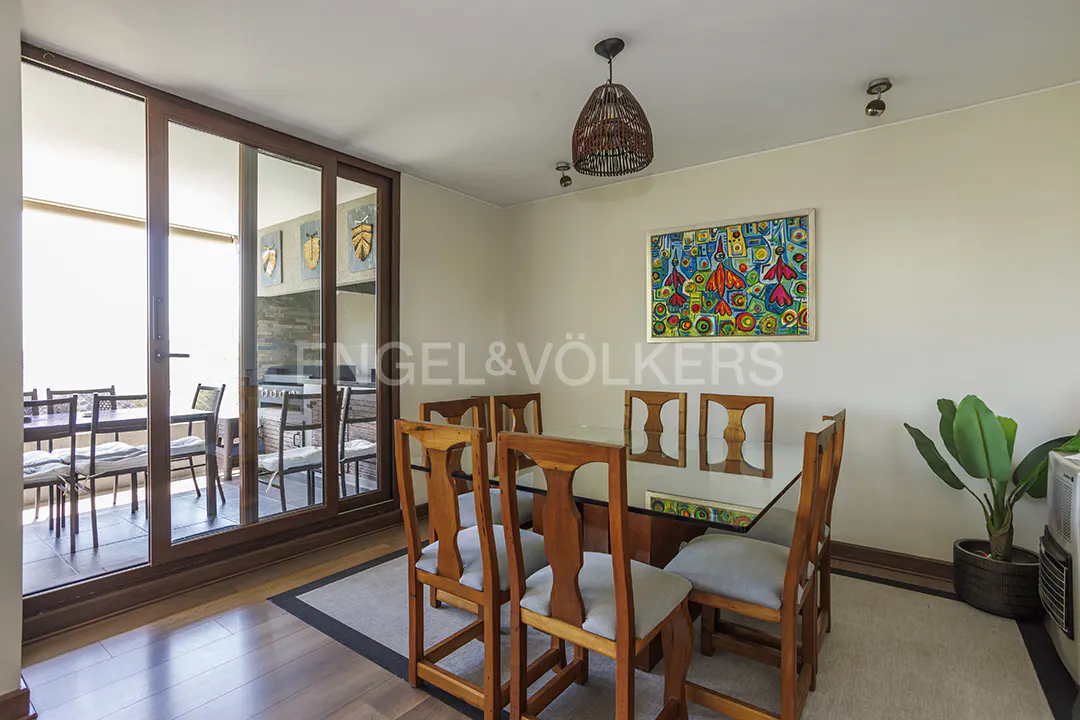 Dining room with a glass table, wooden chairs, and a colorful painting on the wall. A sliding door leads to a balcony.
