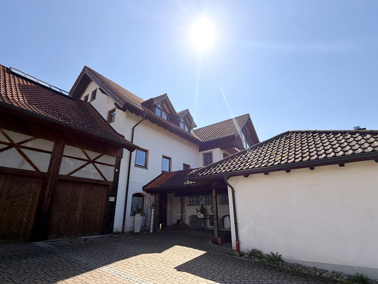 Exterior of a white two-story house with a red tile roof on a sunny day.