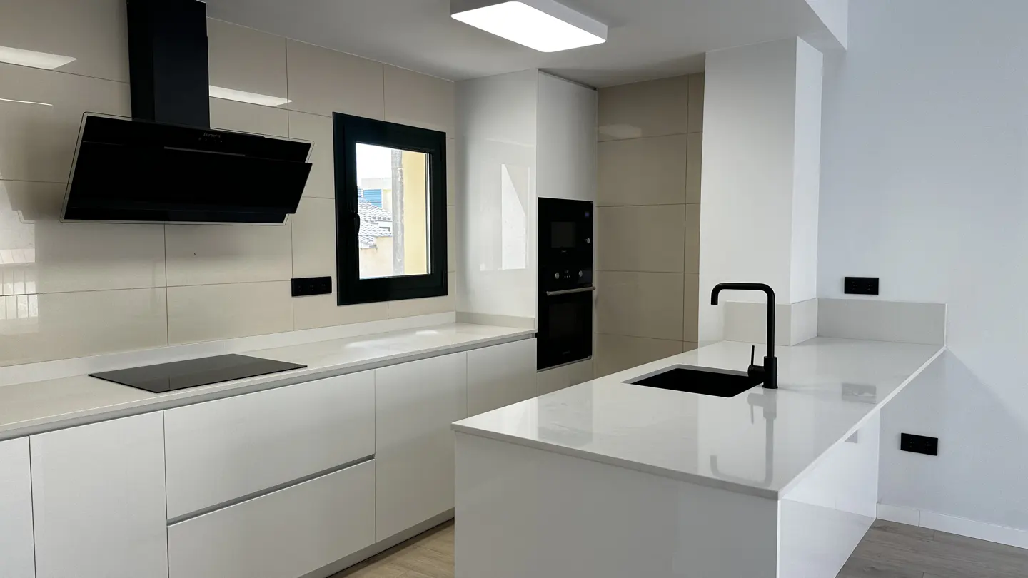 A modern kitchen with white cabinets, countertops, and a black sink, faucet, and appliances.