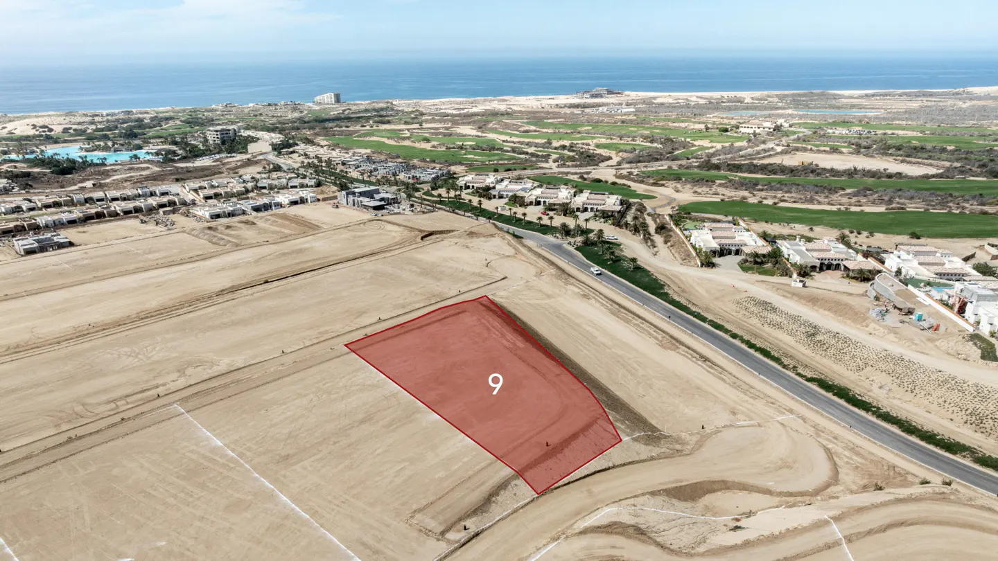 Aerial view of a vacant coastal lot marked with a red overlay and the number 9, near a road, golf course, and the ocean.