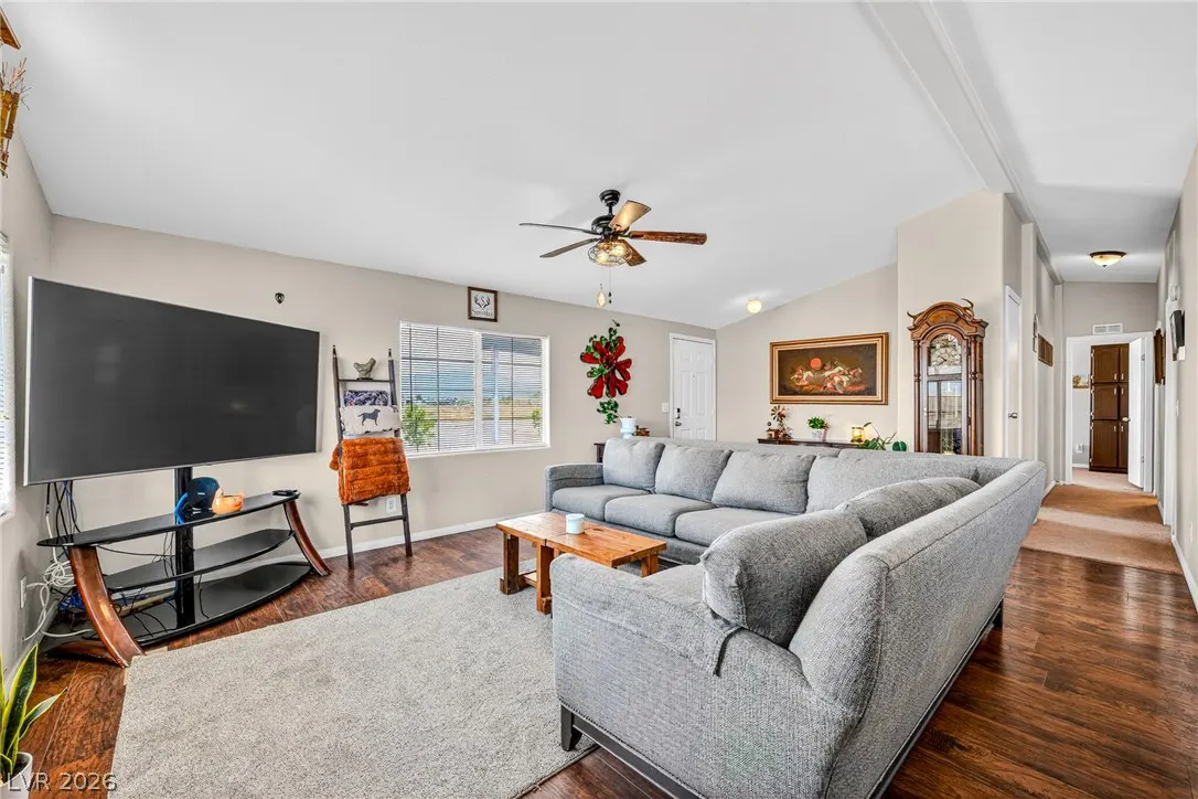 Spacious living room with a large grey sectional, wood coffee table, TV on a black stand, and hardwood floors.
