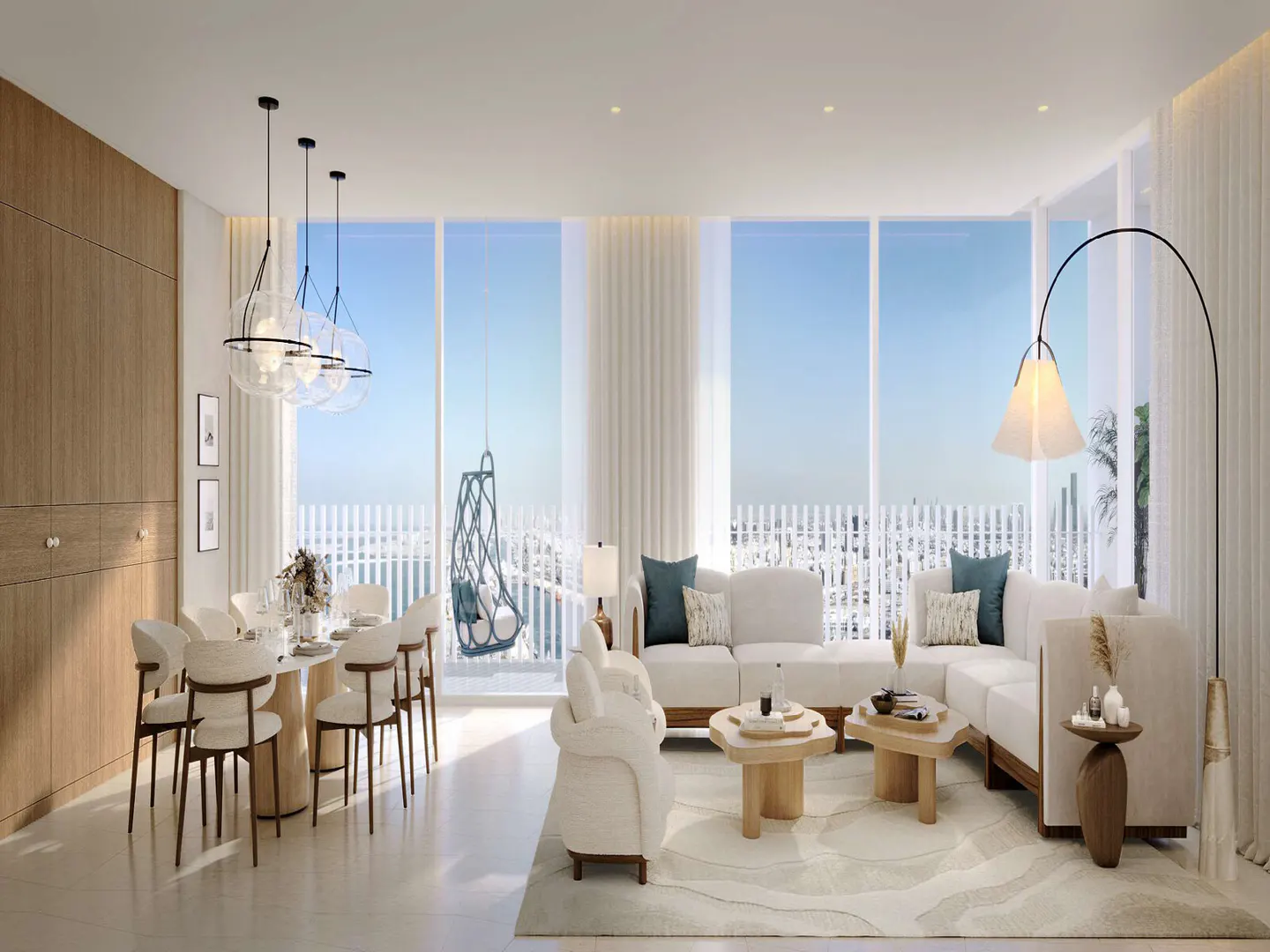 Bright, modern living room with white sectional sofa, wood tables, and dining area. Large windows offer a city view.