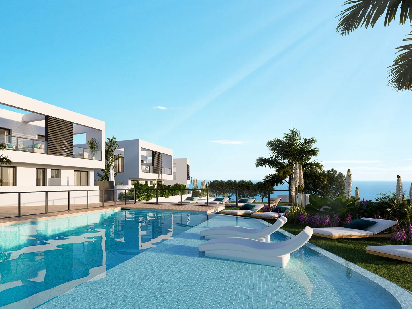 Modern white villas overlook a blue-tiled pool with white lounge chairs. Palm trees and ocean views in the background under a clear blue sky.