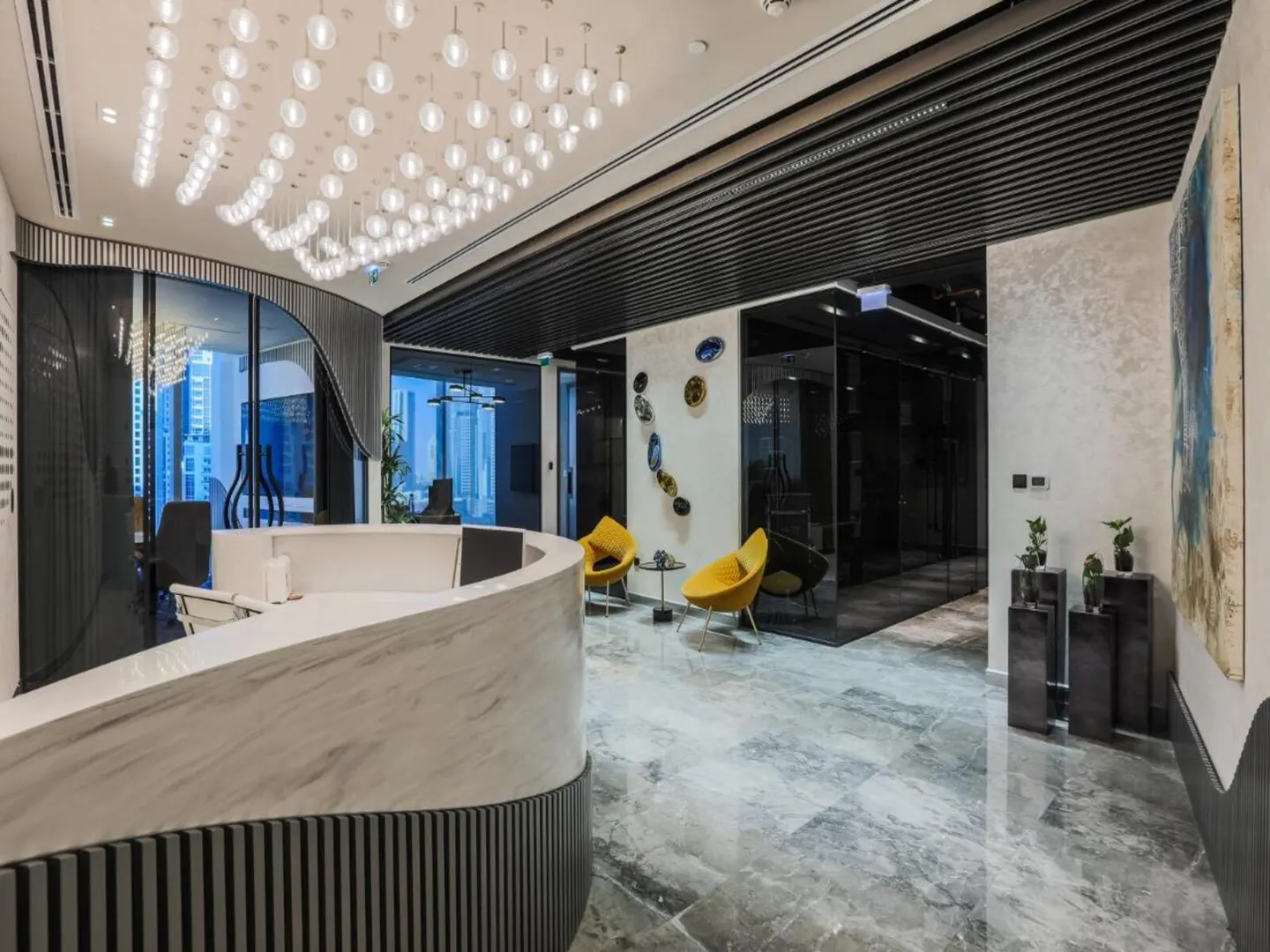 Modern office lobby with a curved marble reception desk, yellow chairs, and globe lighting. Gray marble floors and a large abstract painting.