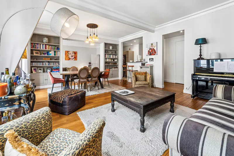 Spacious living room with hardwood floors, a piano, a wooden coffee table, leopard-print chairs, and a dining area.