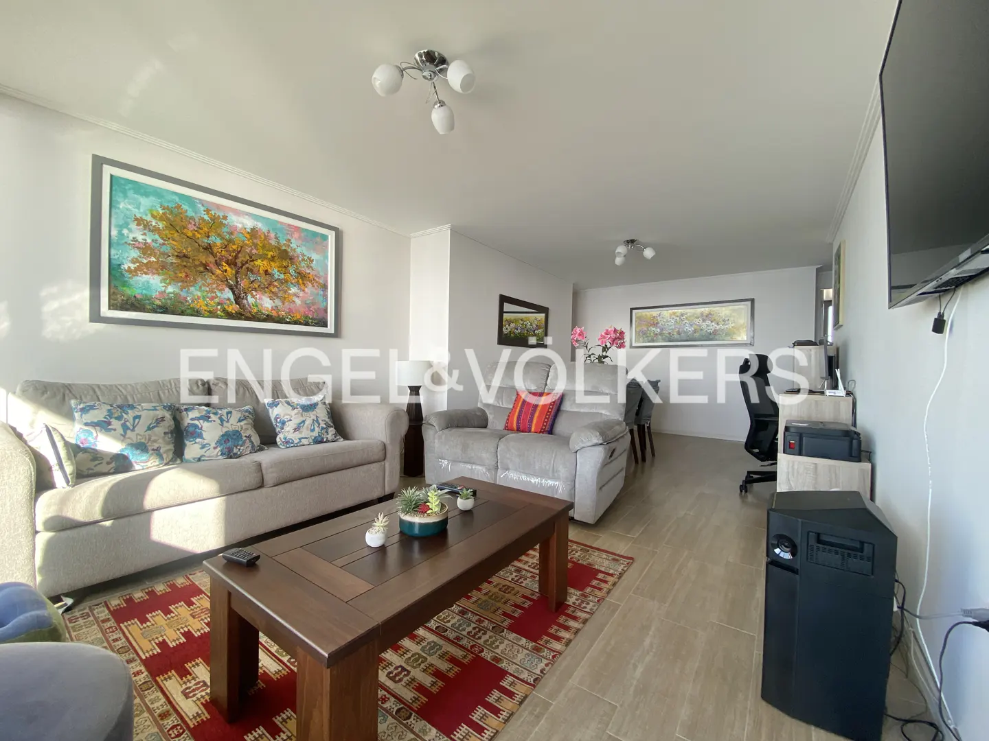 Living room with two gray sofas, a dark wood coffee table on a red patterned rug, and artwork on the walls.