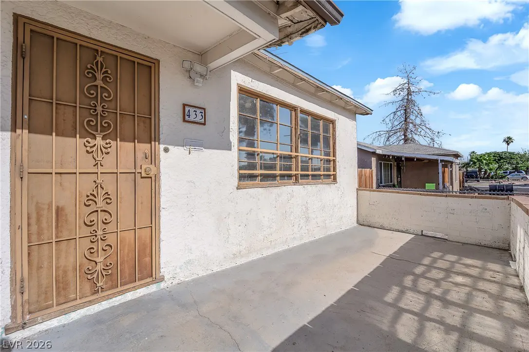 Exterior view of a white stucco house with a brown security door and window. The house number "433" is visible above the door.