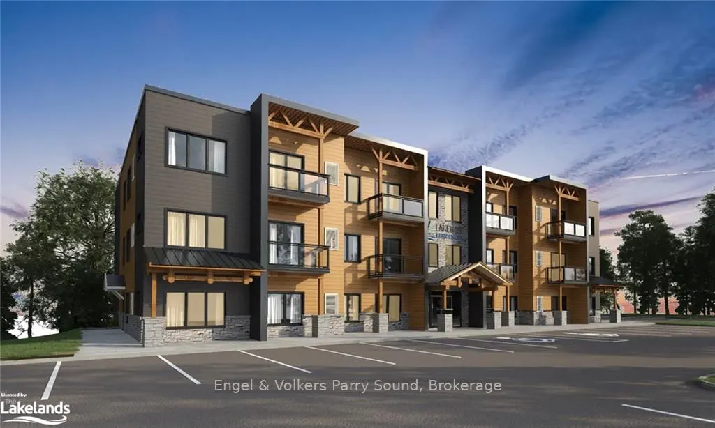 Modern three-story apartment building with wood and gray siding, balconies, and a parking lot under a blue sky.