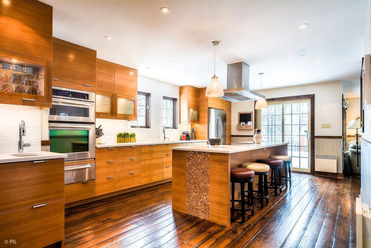 A modern kitchen with wood cabinets, stainless steel appliances, and a center island with stools.