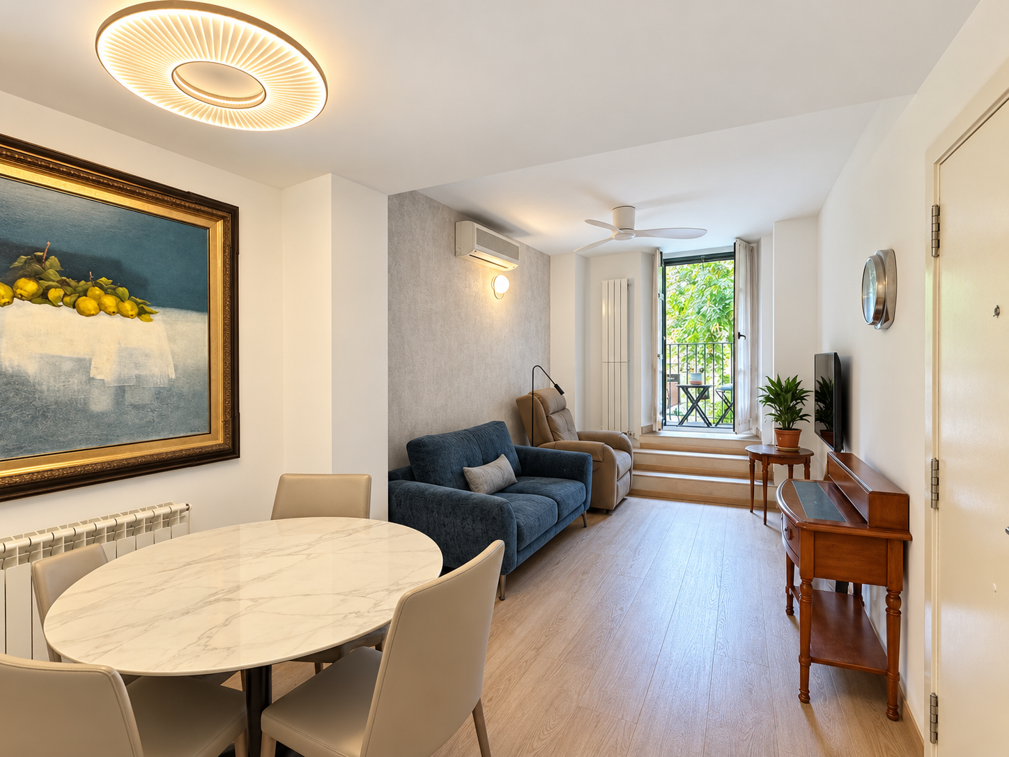 Modern living room with a marble dining table, blue sofa, tan armchair, and a balcony door leading to a green view. [AI-generated text]