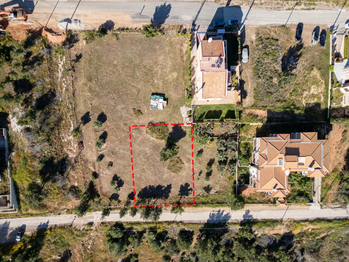 Aerial view of a vacant lot outlined in red, surrounded by houses and greenery.