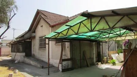 Exterior view of a one-story house with a brown tiled roof and a green carport.