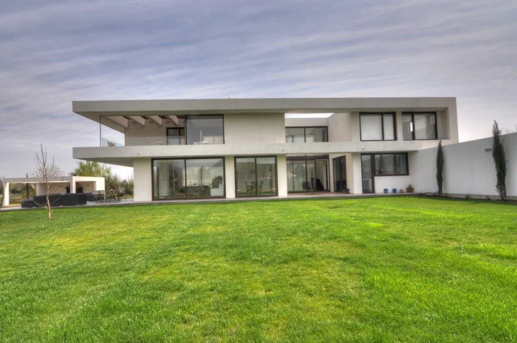 Modern, two-story white house with large windows and a green lawn.