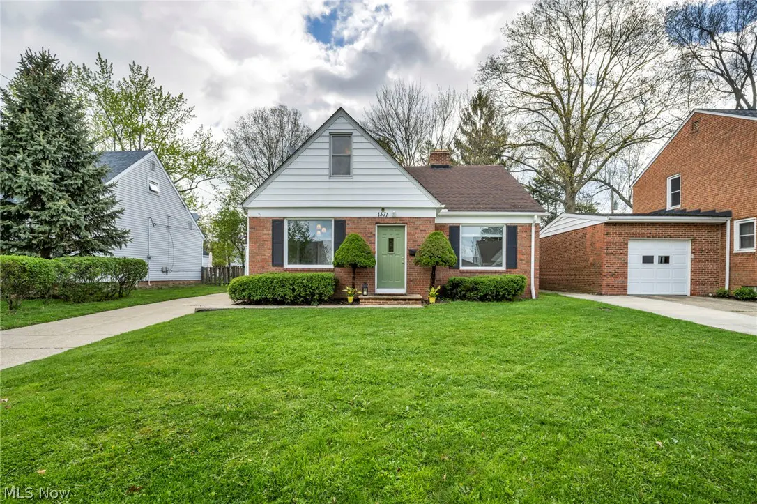 A single-story brick house with a green door and a well-manicured lawn on a cloudy day.