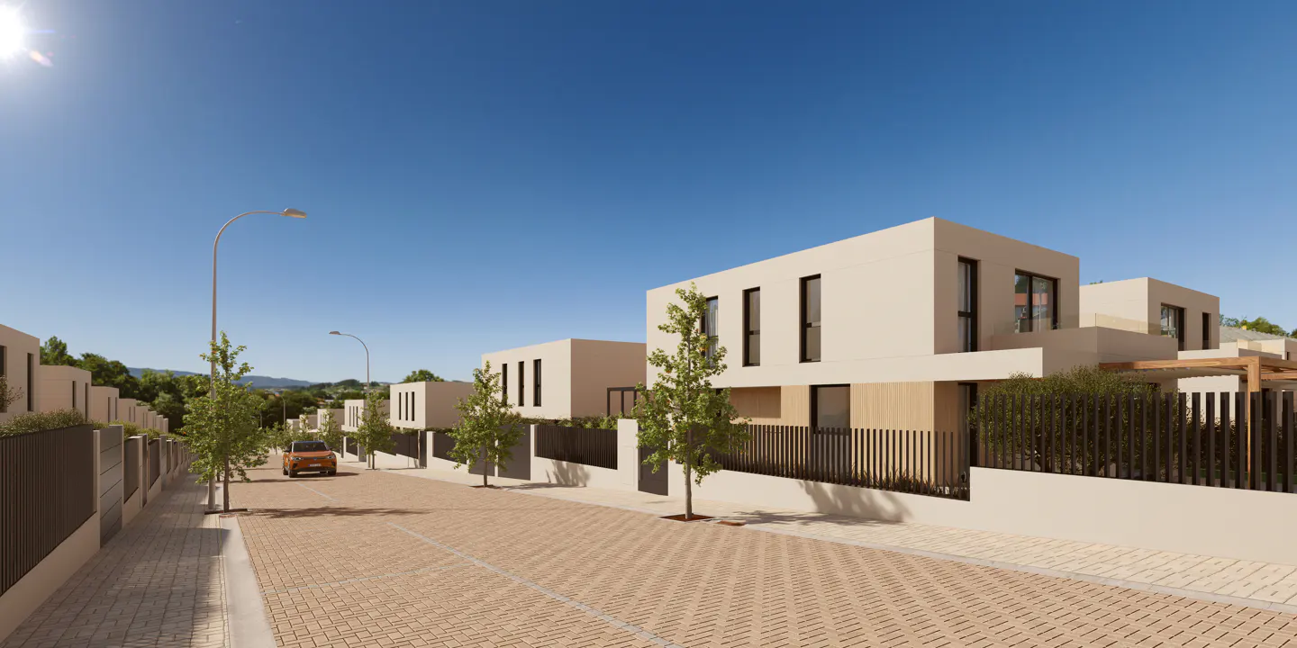 Street view of modern, beige, two-story homes with black-framed windows. A car drives on the brick road under a clear blue sky.