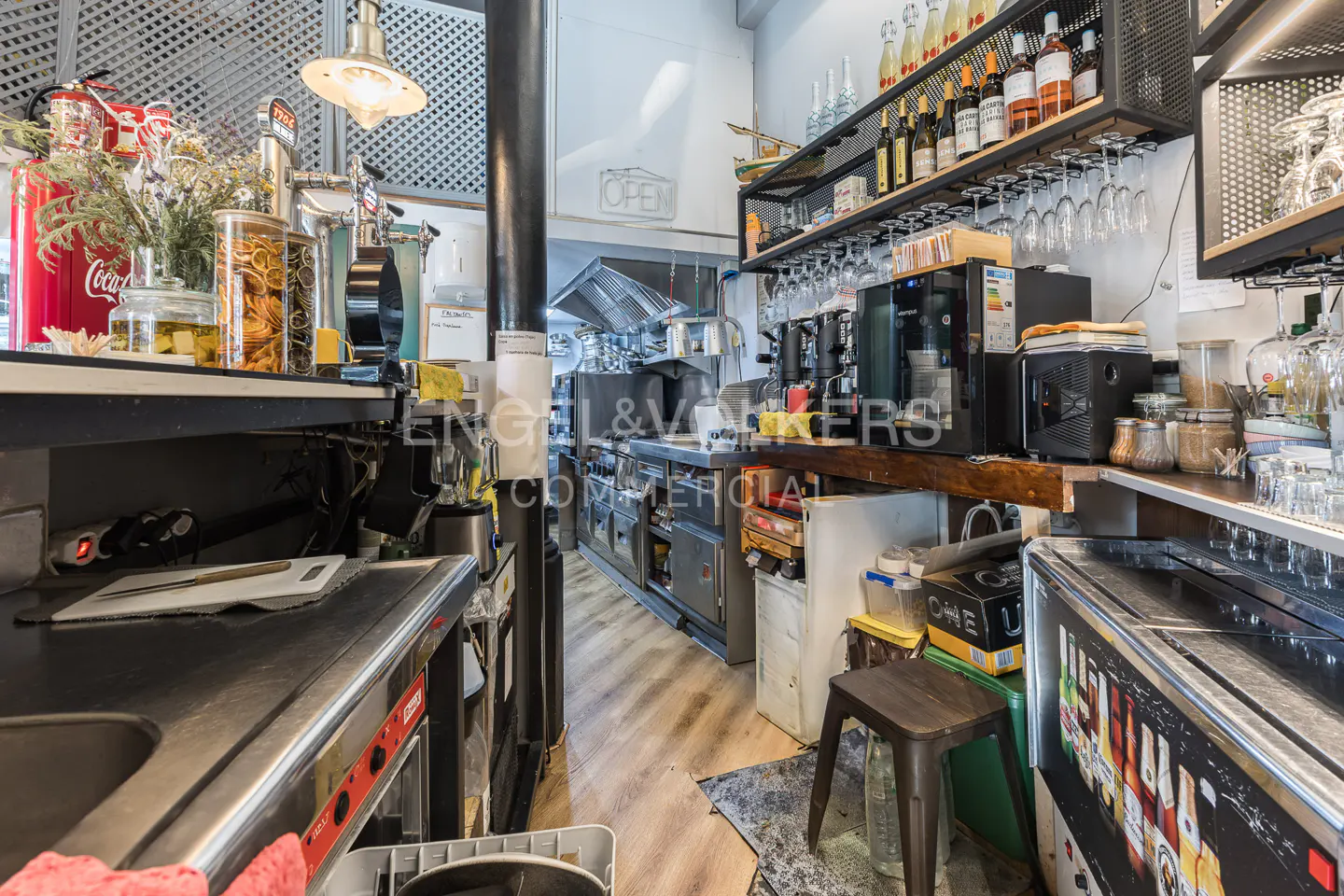 Restaurant kitchen with stainless steel counters, shelves of liquor bottles, and an "OPEN" sign.