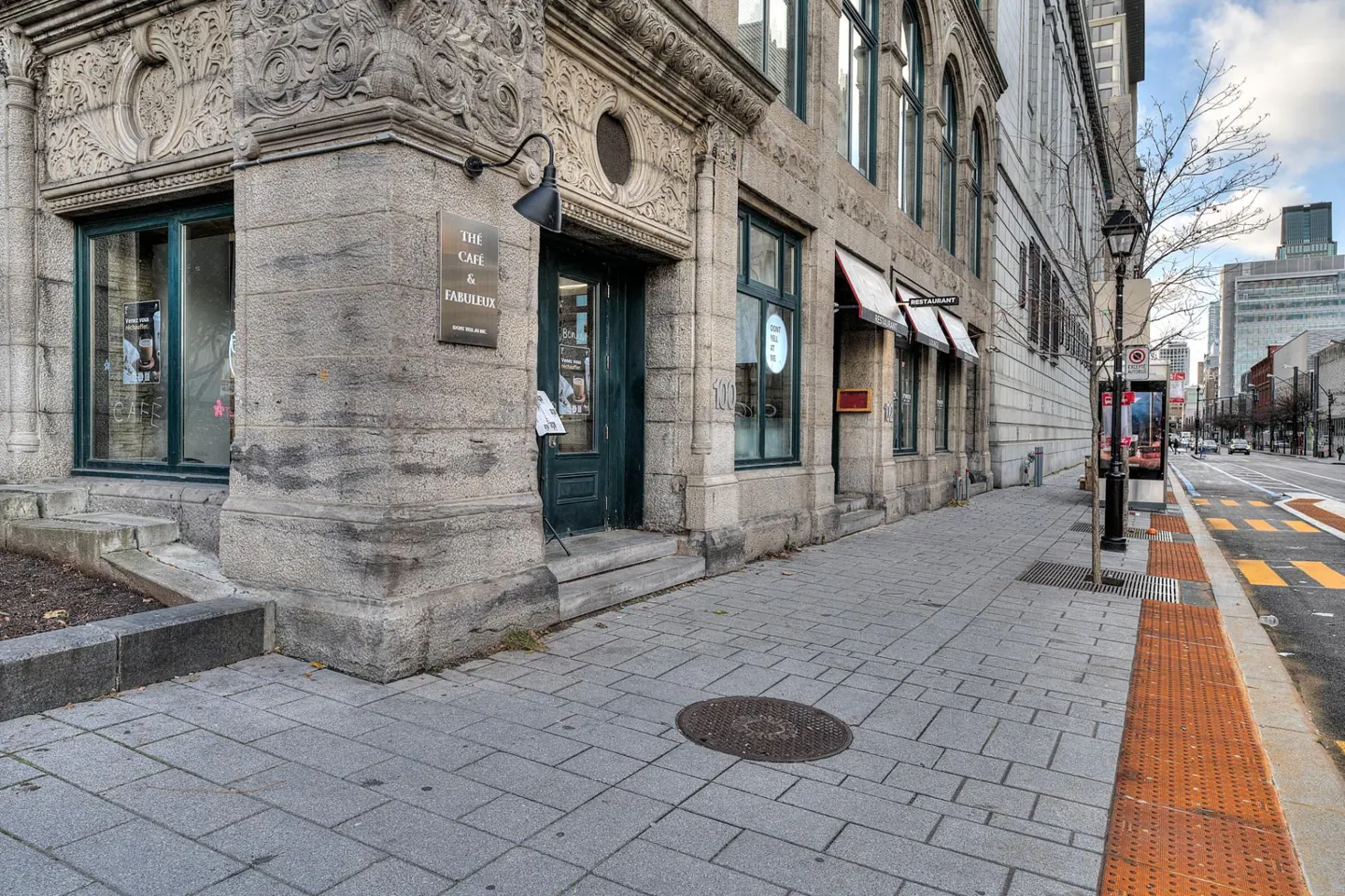 Exterior view of The Cafe & Fabuleux, a stone building with green door and windows on a city street.