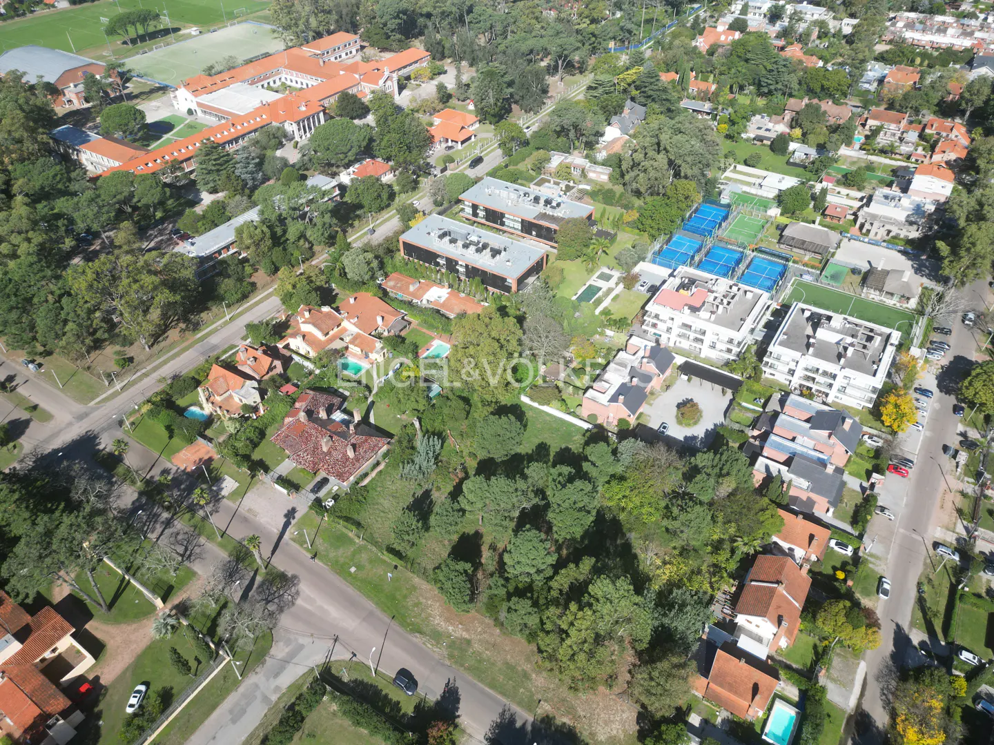 Aerial view of a residential neighborhood with houses, apartments, tennis courts, and green spaces.