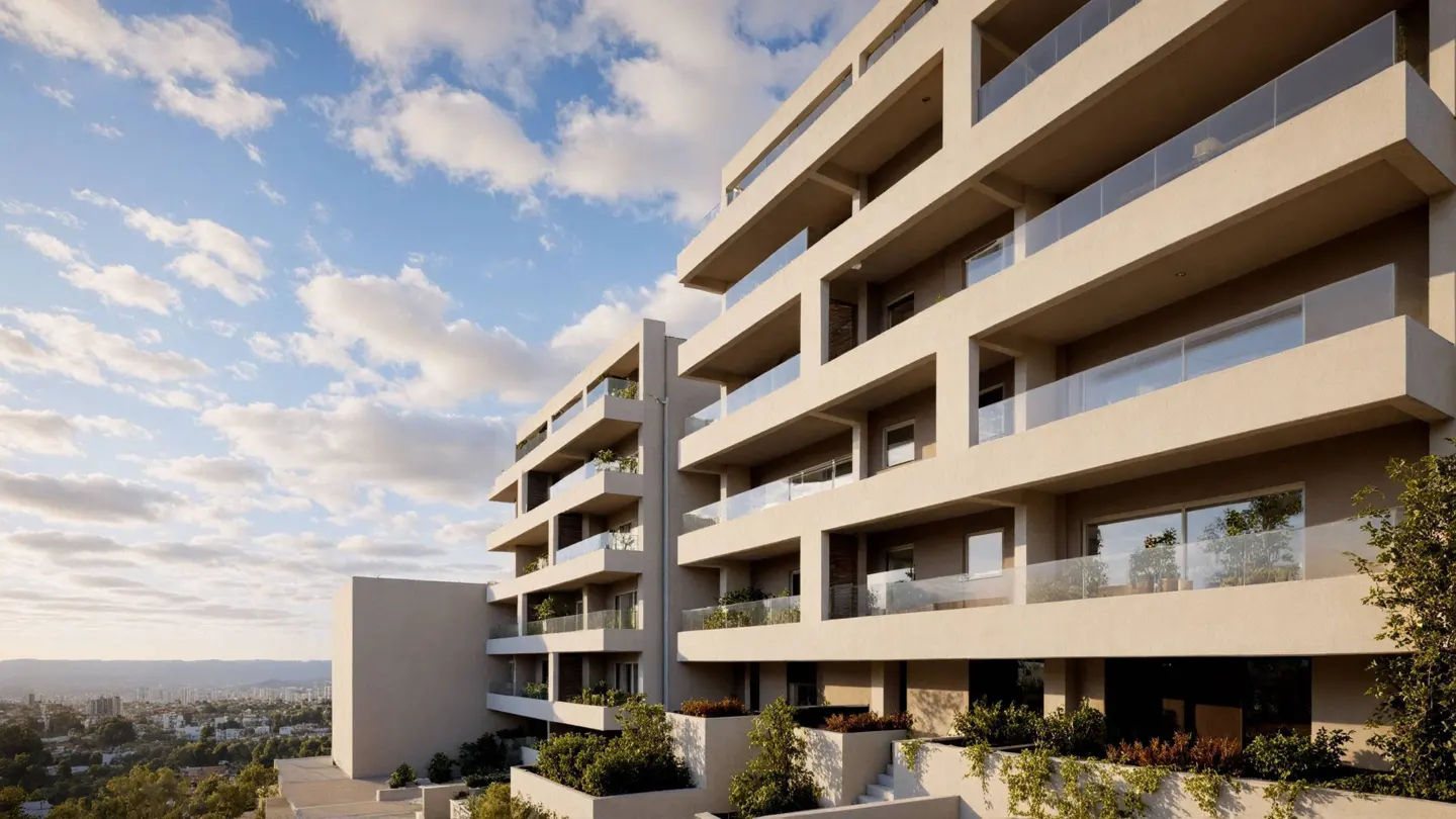 Modern beige apartment building with glass-railed balconies and lush greenery against a blue sky with clouds.