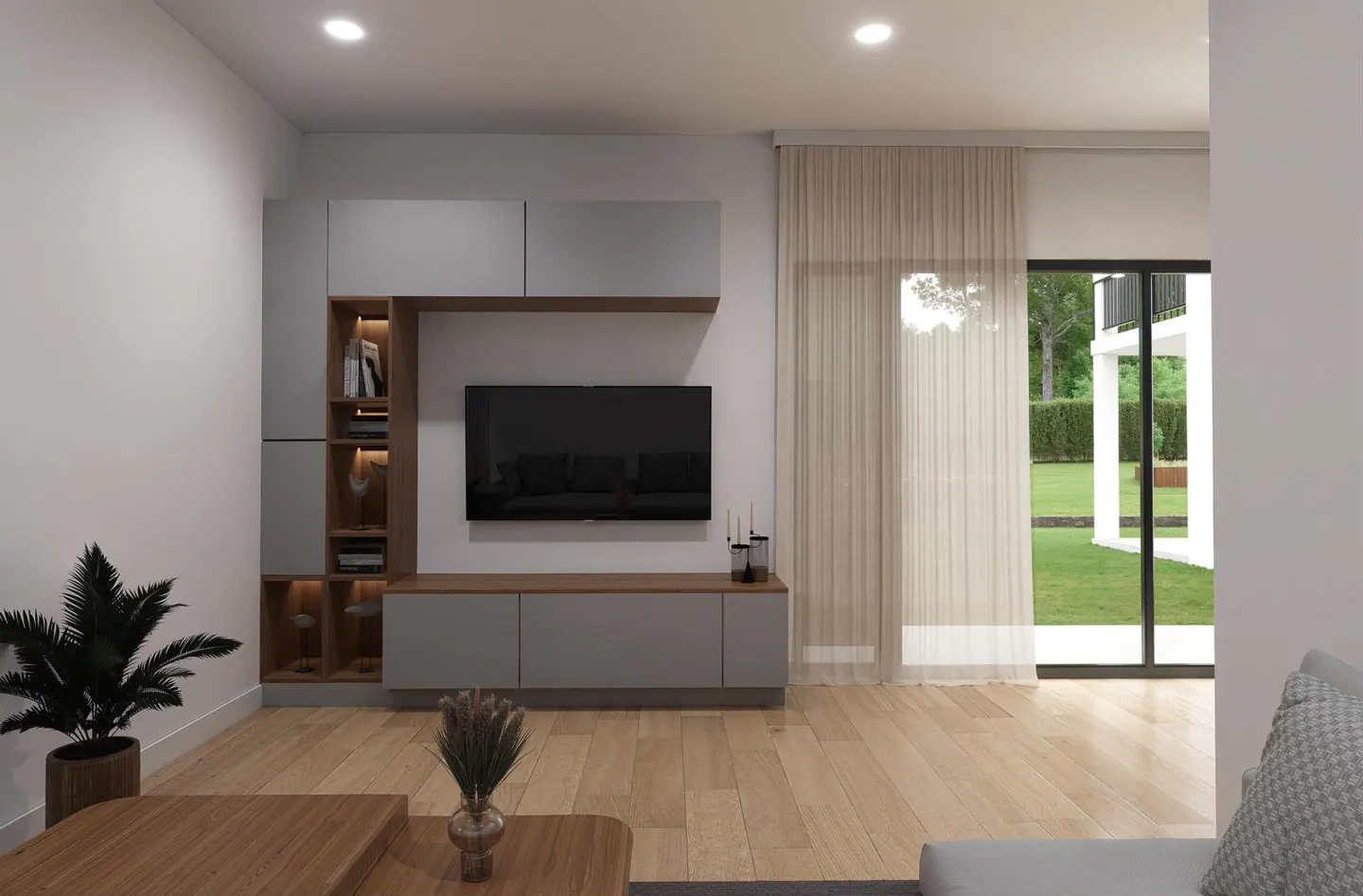 Living room with gray cabinets, a TV, and wood floors. A potted plant sits near a wood coffee table. Sheer curtains cover a glass door to a green lawn.