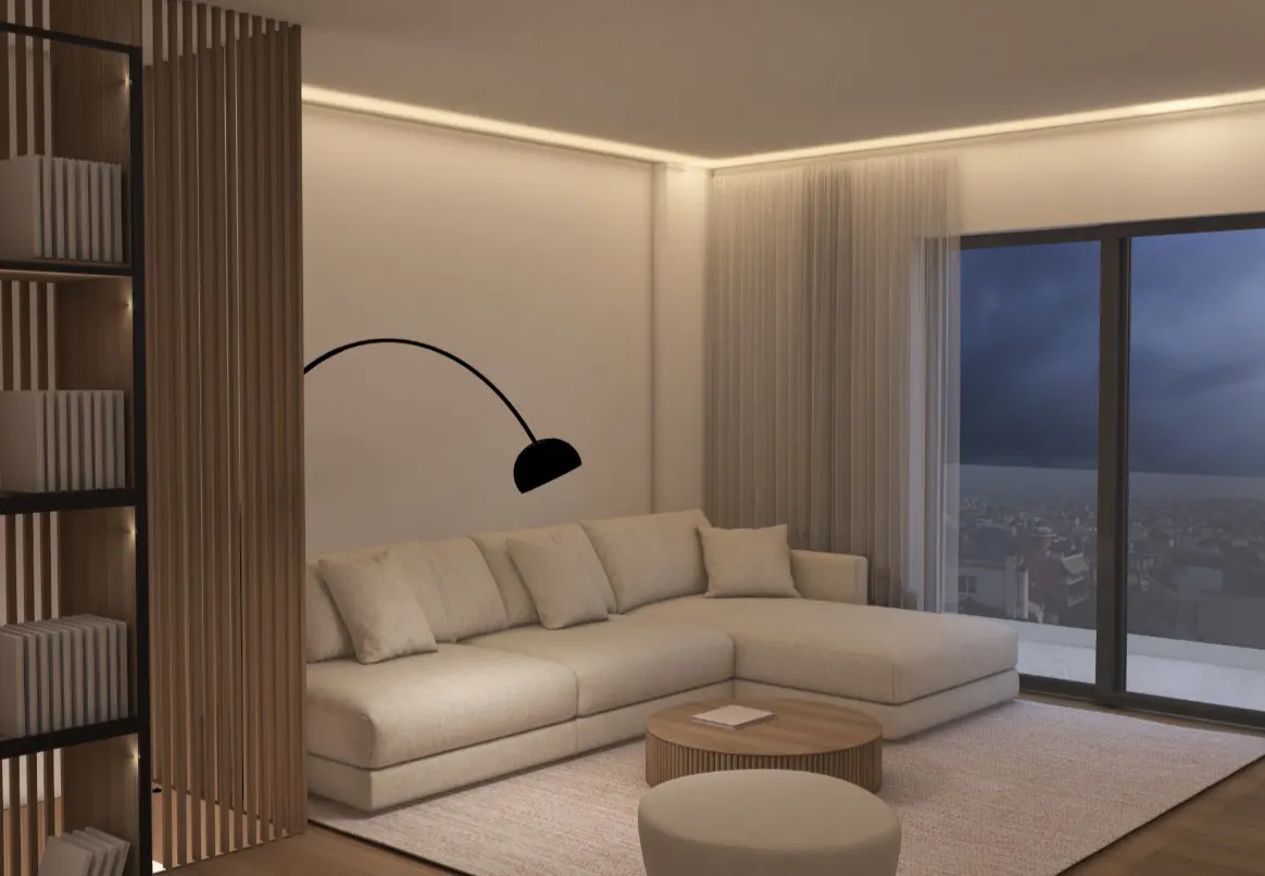 Living room with a beige sectional sofa, round wood table, and ottoman on a light rug. A black arc lamp is behind the sofa. A bookcase is on the left.
