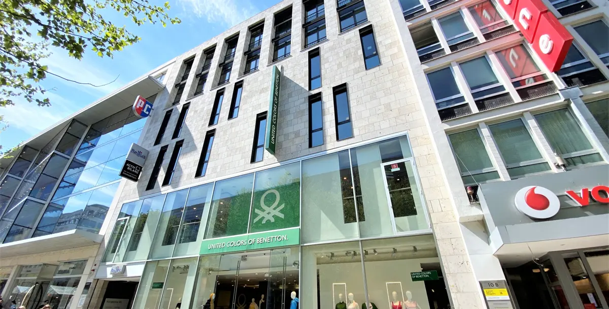 Street view of a United Colors of Benetton store with a green logo and a Vodafone store next door.