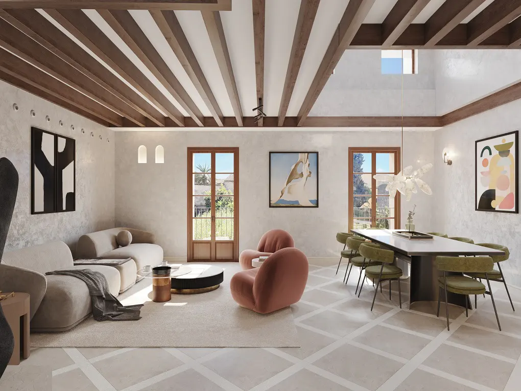A bright, open-concept living and dining area with beige sofas, pink chairs, and a long dining table with green chairs. The ceiling has exposed wooden beams.