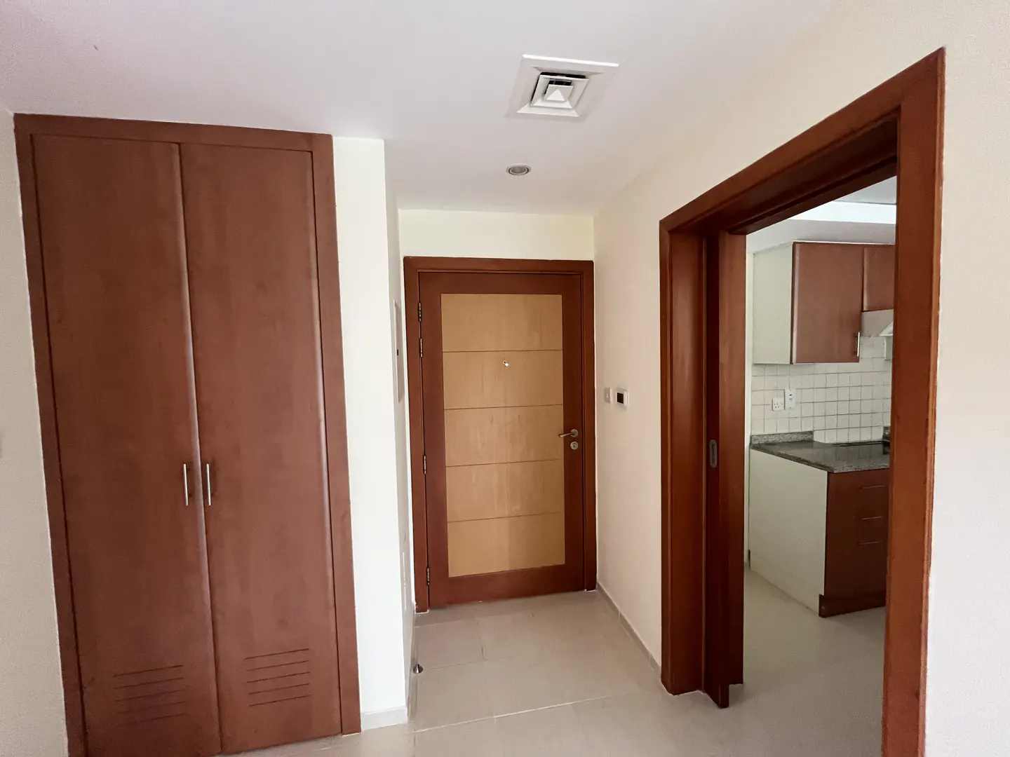 A bright hallway with a closet, a front door, and an open doorway to a kitchen.