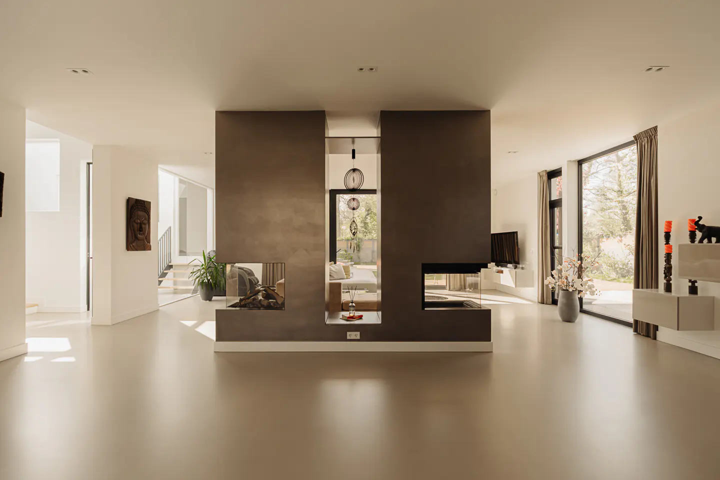 A modern living room with a central brown divider featuring fireplaces and a view to the outside.