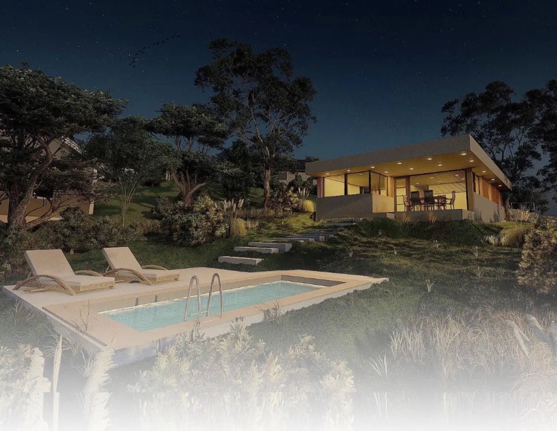 Modern house with pool at night. Lounge chairs sit poolside, with a lit house on a hill in the background.