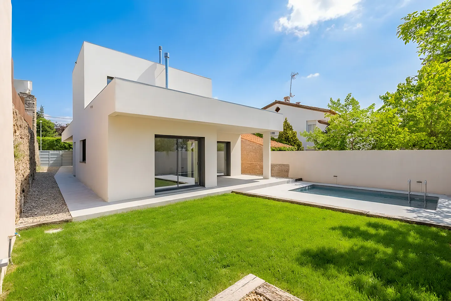 Modern white house with a green lawn and a swimming pool under a blue sky.