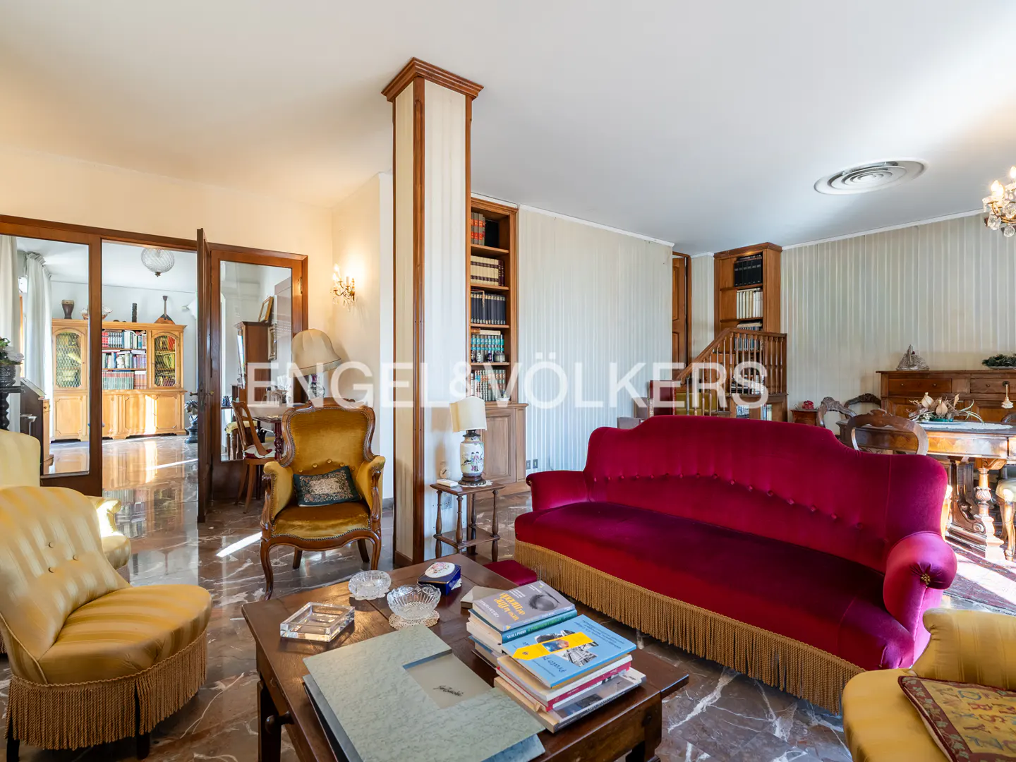 A living room with a red sofa, yellow armchairs, and a wooden coffee table with books.