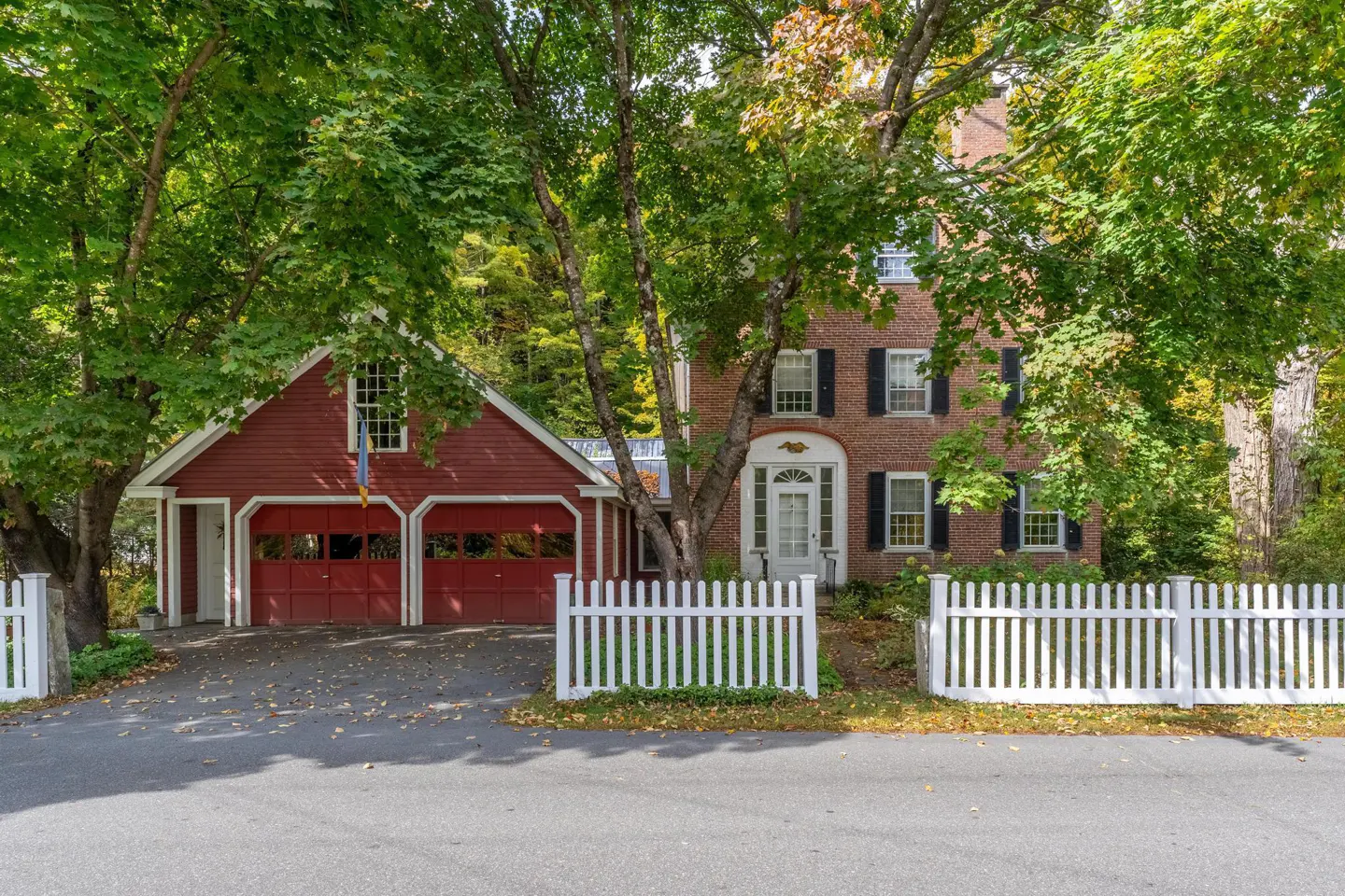 A two-story brick house with a red garage and a white picket fence.