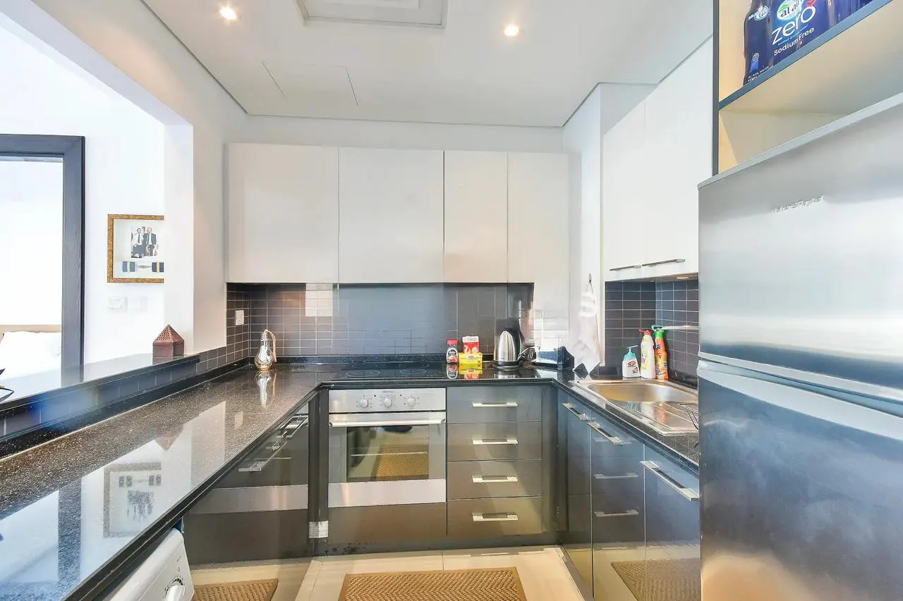 A modern kitchen with black countertops, white cabinets, and stainless steel appliances.